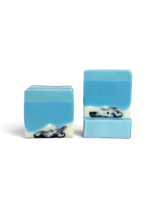 Three rectangular handmade soap bars with a blue and white mountain landscape design, featuring a black and white cloud swirl near the bottom, set against a plain white background.