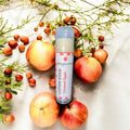 Lotion stick with 'Caramel Apple' scent surrounded by apples and foliage on a light background