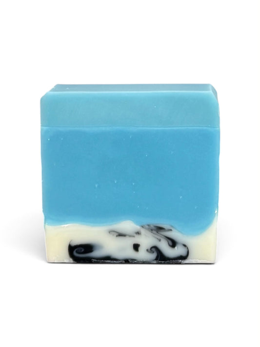 A rectangular bar of handmade soap with a light blue top half and a bottom half featuring a swirl of white and black, set against a plain white background.