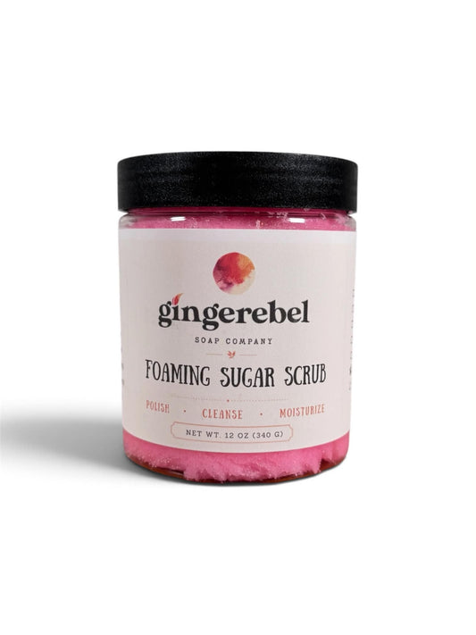 A jar of Gingerebel Foaming Sugar Scrub with a black lid and a white label, set against a plain white background.
