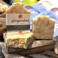 three oats and honey bar soaps on a log. 