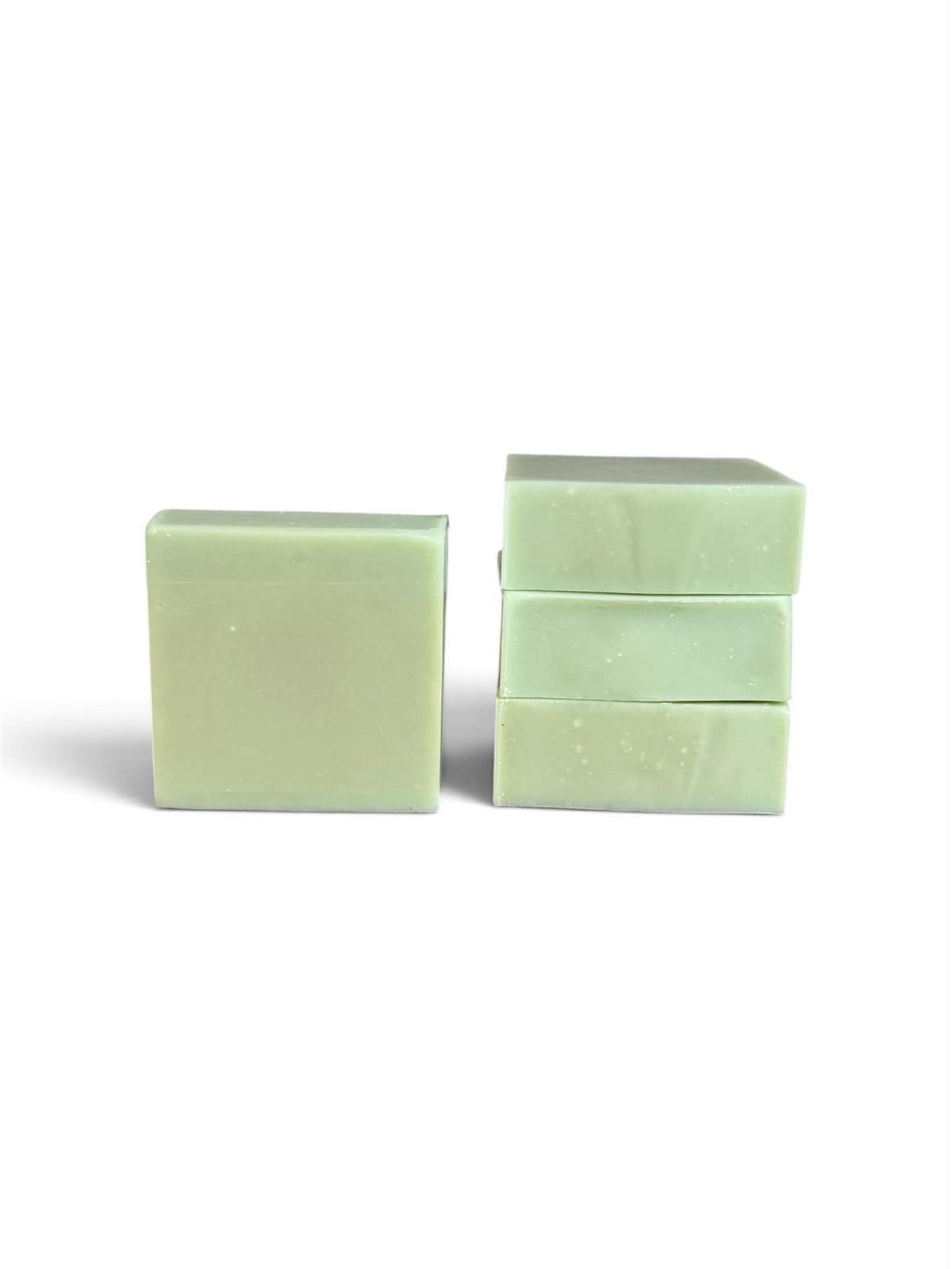 Three pale mint green rectangular bars of soap standing upright on a white background, with one bar standing alone on the left and two stacked on the right.