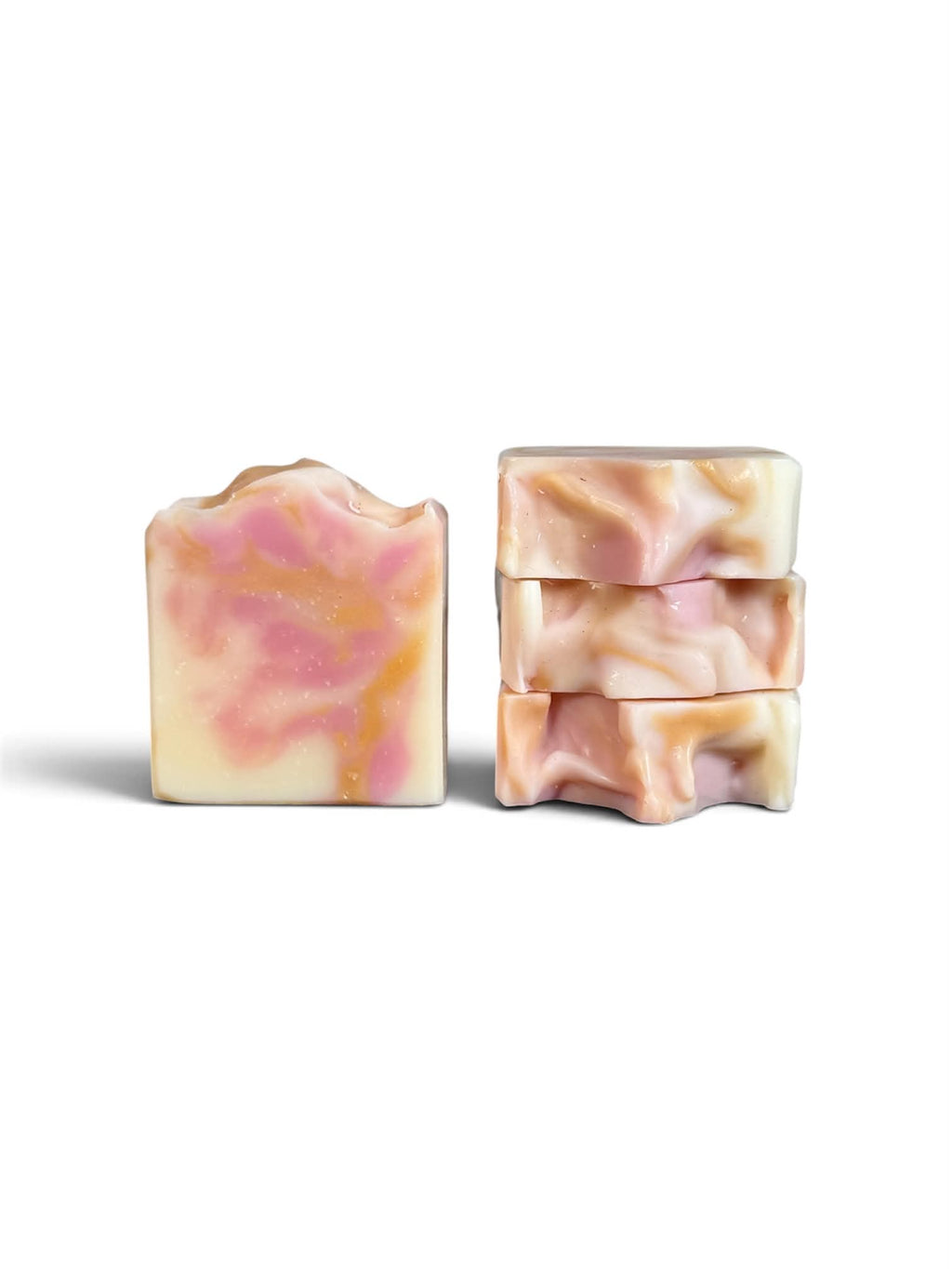 4 bars of soap. 3 stacked on top of each other showcasing the top of the soap and one standing upright showing the pink, gold, and cream colors. 