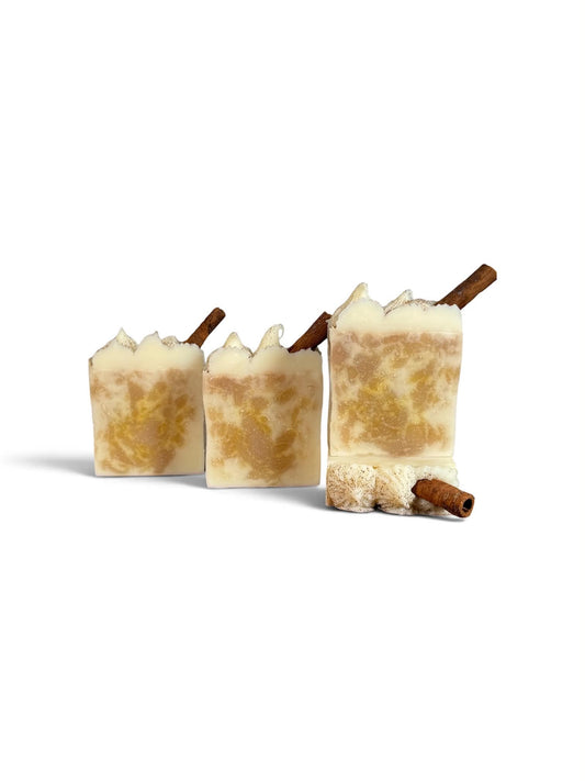 4 square soaps with cream and orange swirls and a cinnamon stick on top