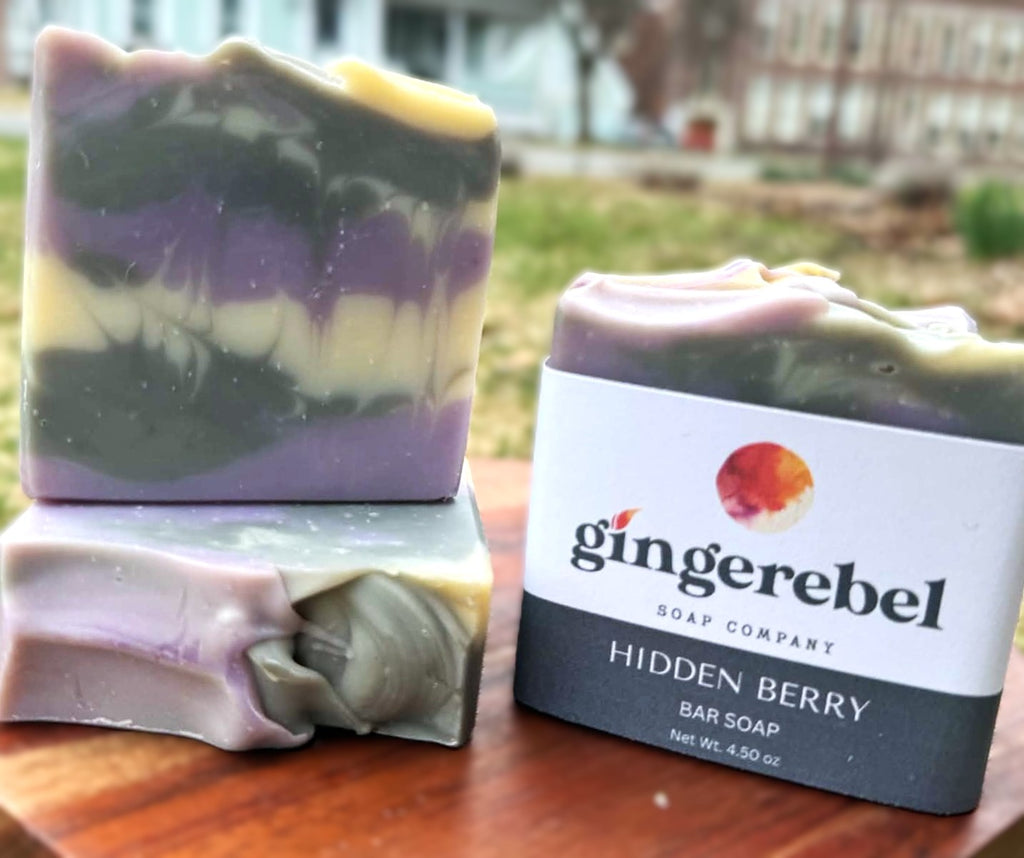 Three bars of soap with a 'gingerebel' label on a wooden surface outdoors.