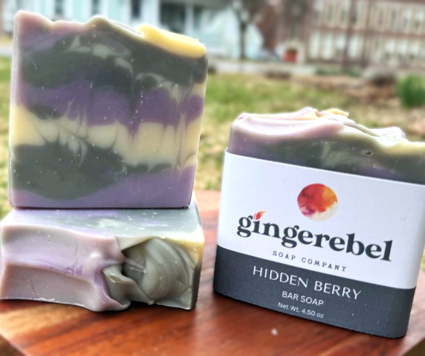 Three bars of soap with a 'gingerebel' label on a wooden surface outdoors.