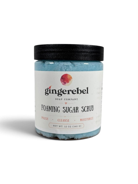 A jar of blue sugar scrub with a white label on a white background. 