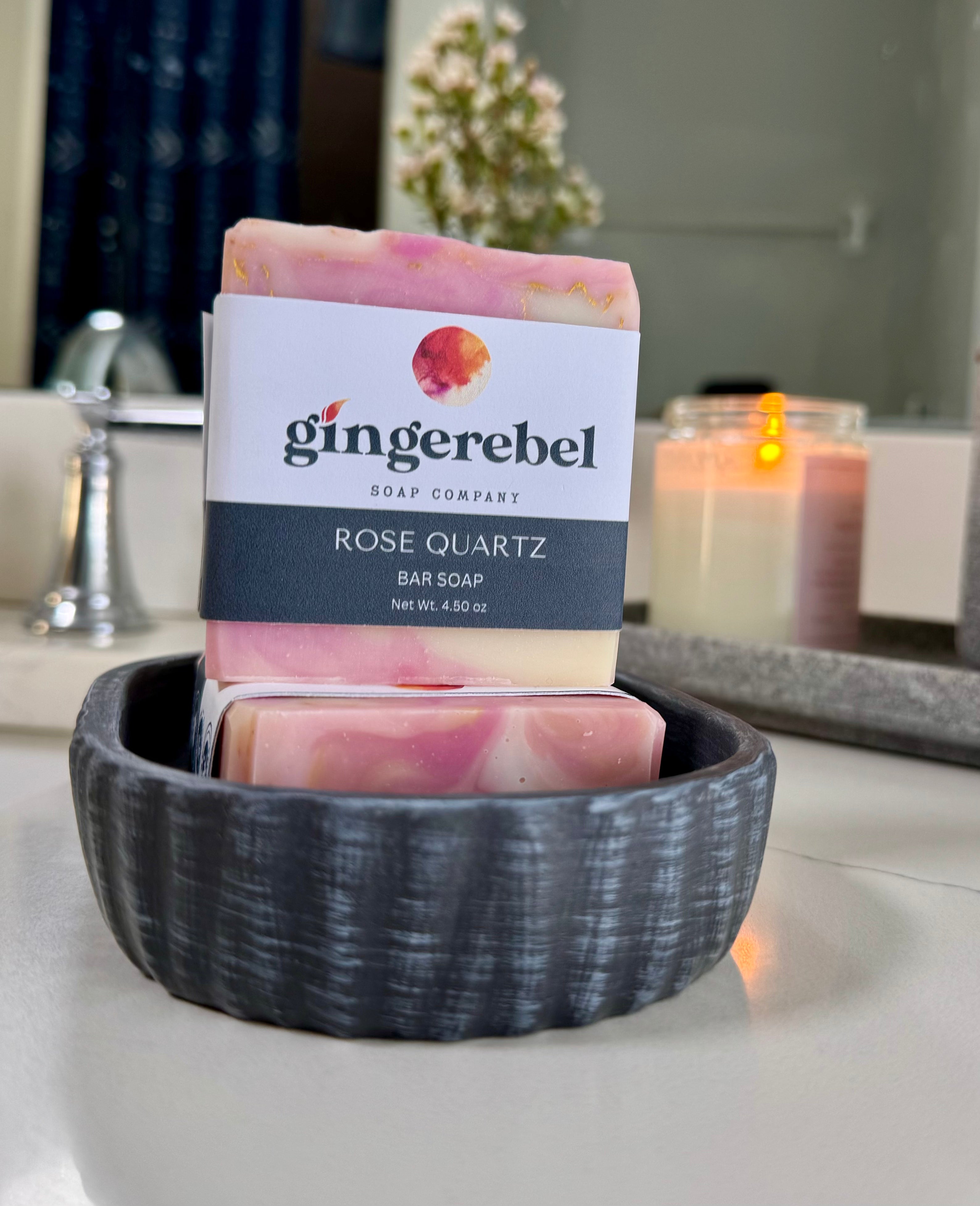 Bar of soap with 'gingerebel' label in a black bowl on a bathroom counter.