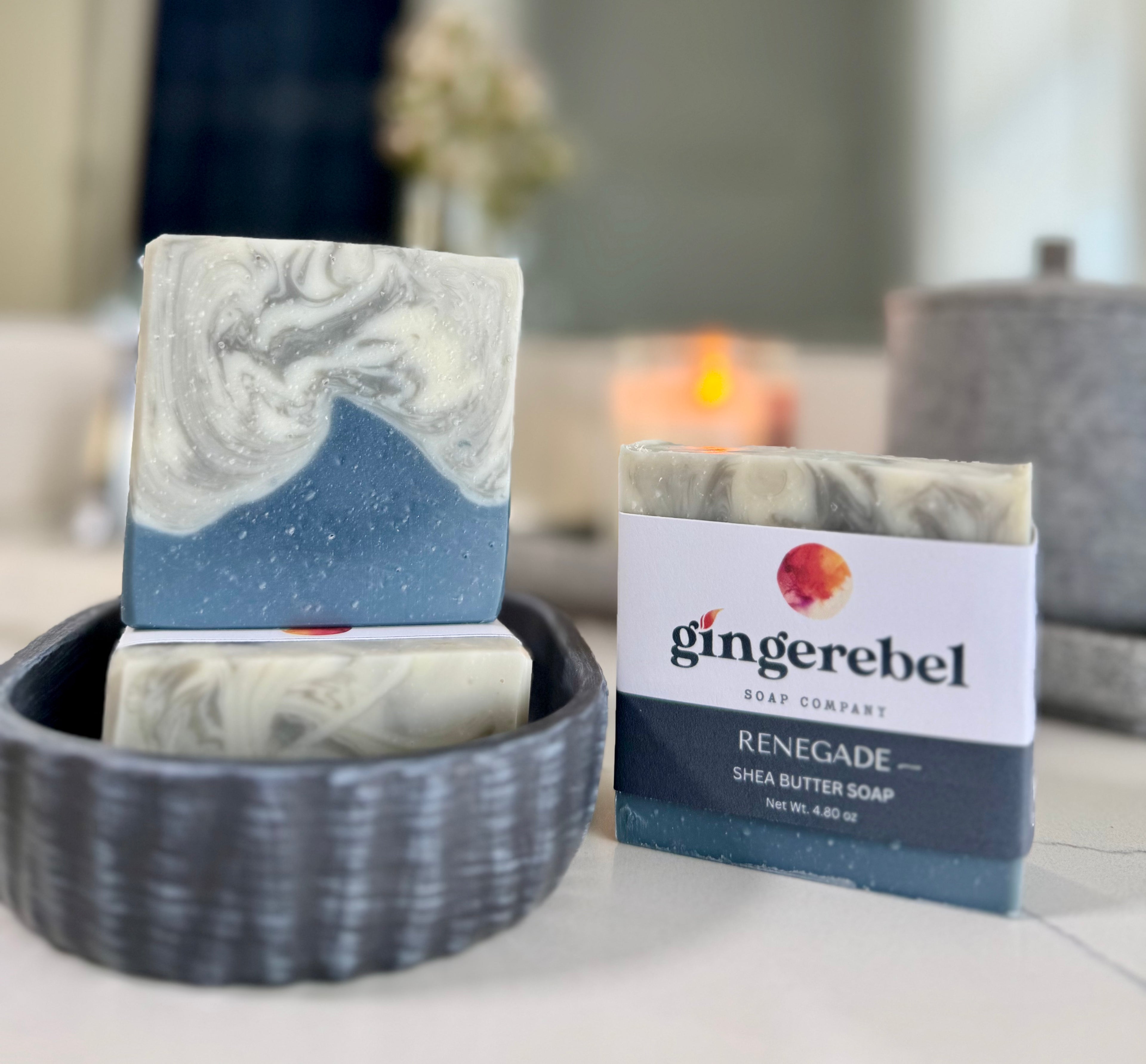 Marble-patterned soap bars in a bowl with 'gingerebel' packaging on a blurred background