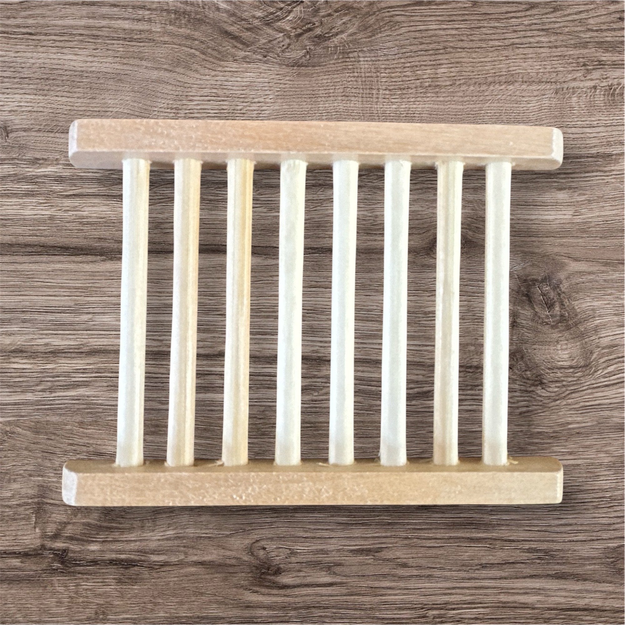 A beige bamboo soap dish with multiple compartments, placed on a wooden surface.