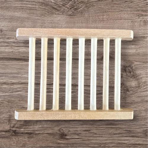 A beige bamboo soap dish with multiple compartments, placed on a wooden surface.