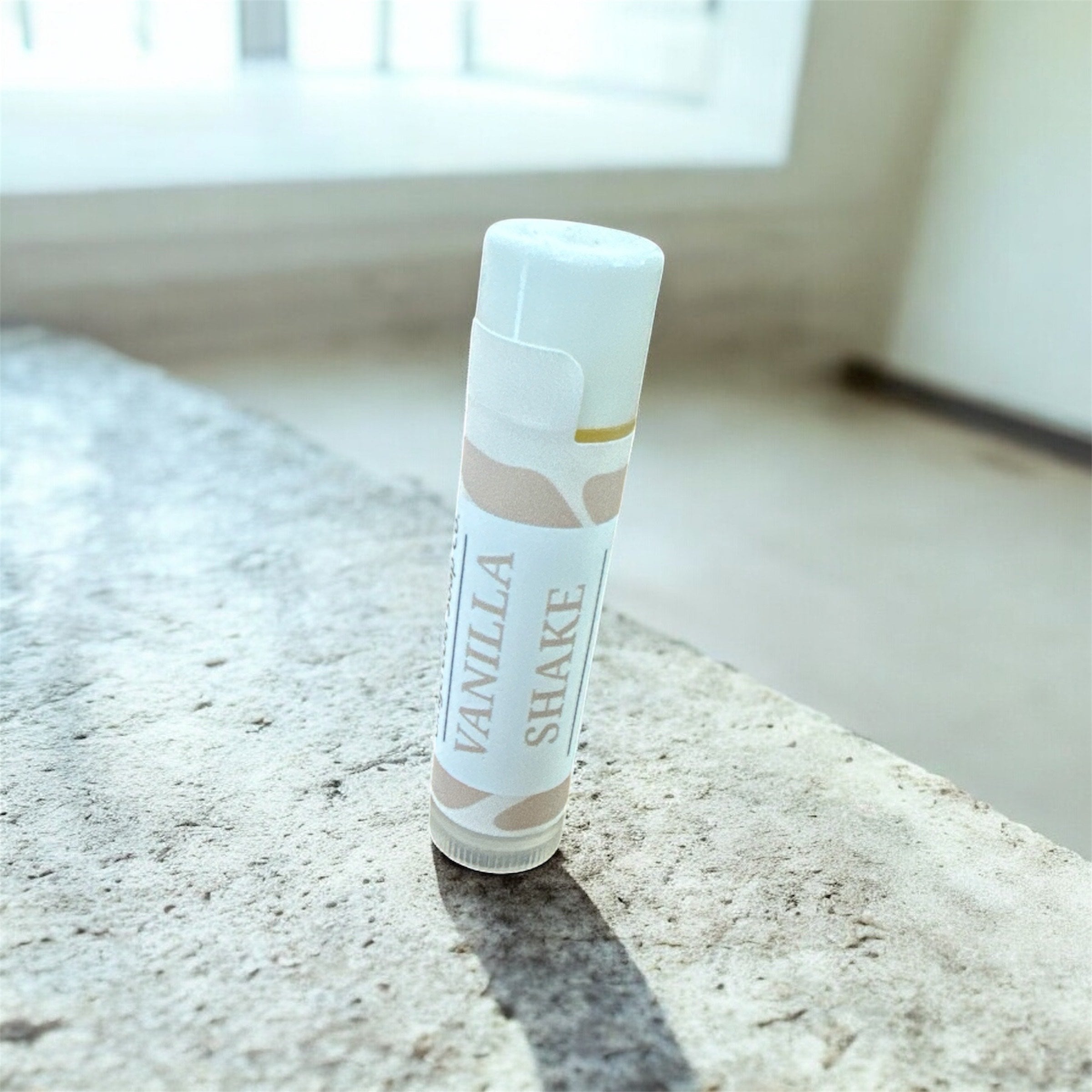 Vanilla Shake lip balm on a marble surface with a blurred background