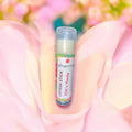 Lotion stick with colorful label scented with wild n peachy, on a soft pink floral background