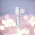 Lotion stick scented in blushing amber with gingerebel branding on a blurred lights background