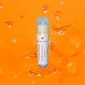 Lotion stick of pumpkin coconut cream on an orange background with water droplets