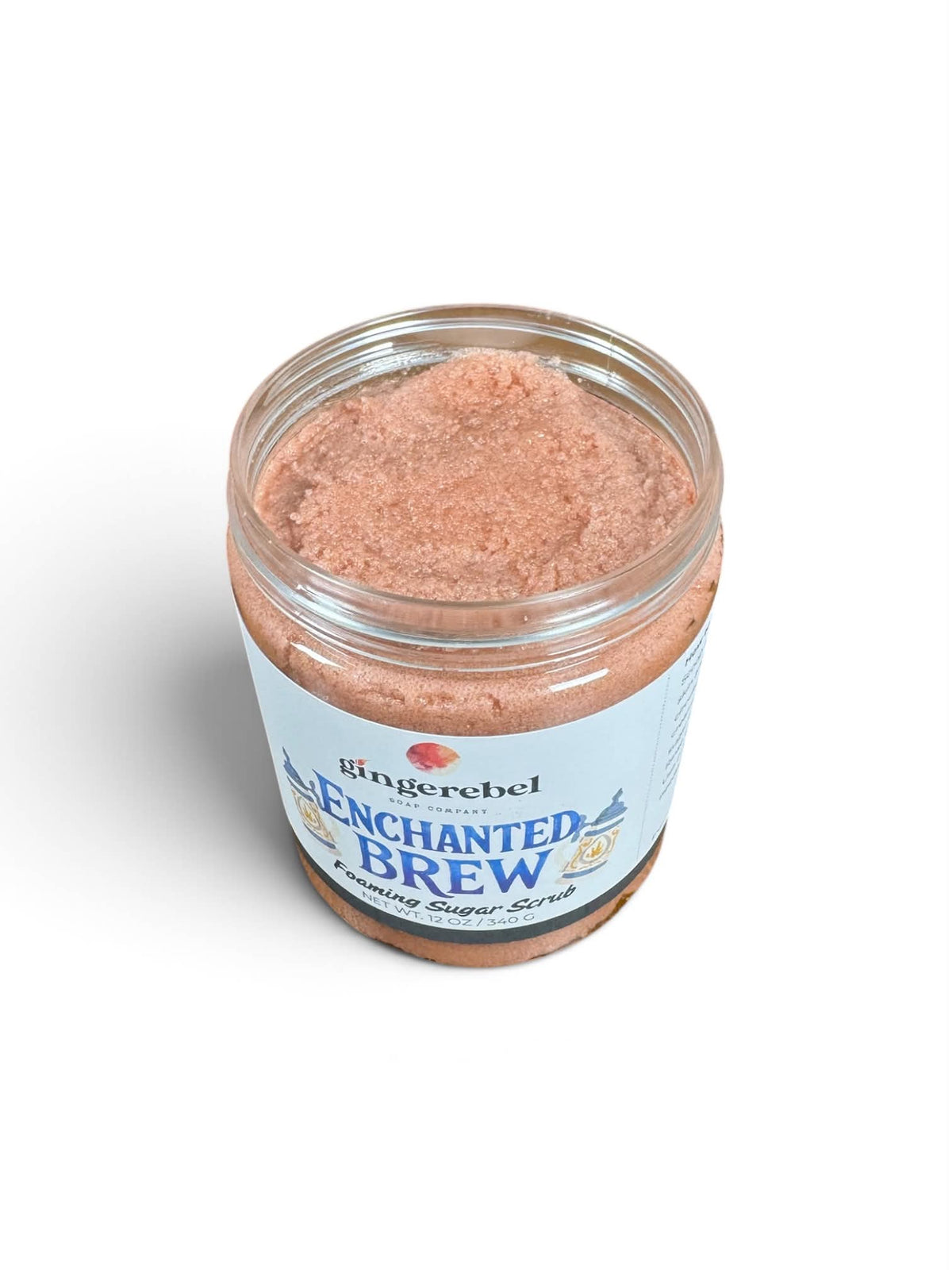 A clear jar of Gingerebel Enchanted Brew Exfoliating Super Scrub showing the pinkish-brown exfoliating scrub inside, set against a plain white background.