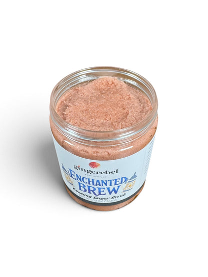 A clear jar of Gingerebel Enchanted Brew Exfoliating Super Scrub showing the pinkish-brown exfoliating scrub inside, set against a plain white background.