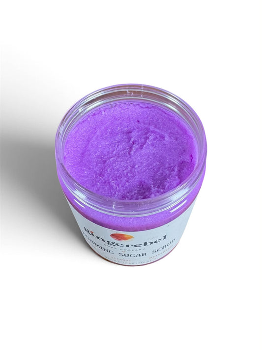 A clear plastic jar filled with bright purple organic sugar scrub, shown from a top-down angle on a white background. 
