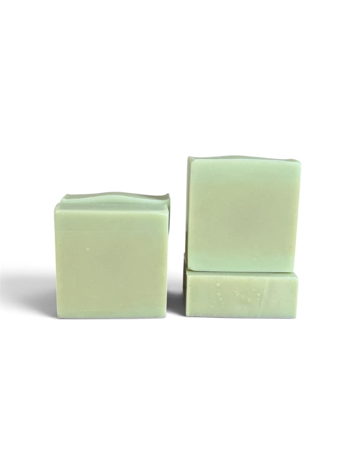 Two pale mint green bars of soap standing upright on a white background, one standing alone and the other stacked with a smaller piece in front.