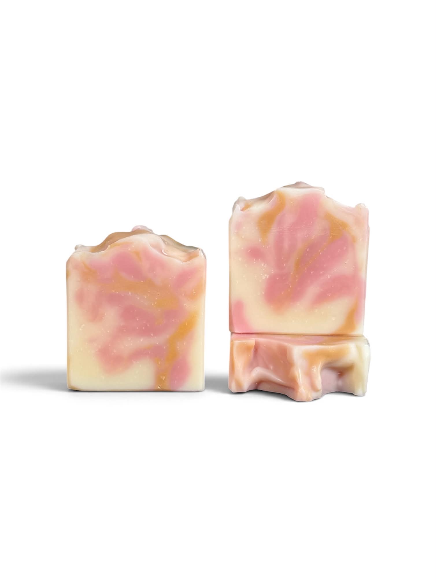 Two handmade rectangular bars of soap with a pink, peach, and cream marbled swirl pattern, displayed on a clean white background.