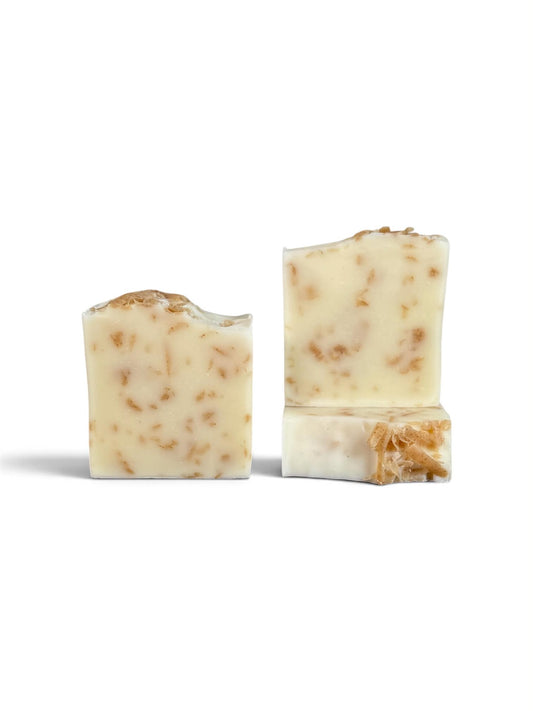 Three rectangular bars of handmade soap with a creamy off-white base and embedded brown botanical pieces, displayed on a clean white background.